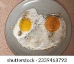 Small photo of Indulge in the simple pleasures of breakfast with two sunny side up eggs. Witness the golden yolks, one soft orange, the other pale yellow, ready to burst with flavor. A sprinkle of freshly ground pep