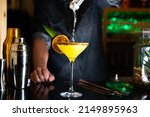 Small photo of Bartender pouring alcohol on a cocktail in a night club bar
