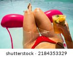 Woman in red bikini on a inflatable mattress having a mojito cocktail inside the swimming pool in summer
