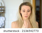 Small photo of Forty year old woman looking at a tuft of her hair in her hand appalled at the hair loss at her age