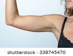 Middle aged woman wearing black laced bra while showing flabby arm, effect of aging caused by loss of elasticity and muscle, close-up