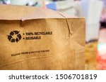 Brown paper bag that is 100% recyclable and reusable on a counter. A printed plea for user to recycle and reuse this bag as a form of packaging.
