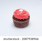 Small photo of Chocolate cupcake decorated with red pink icing and sprinkles isolated on white