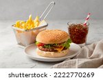 Fresh tasty burger, french fries and soft drink on dark background