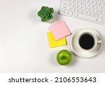 Top view of  Green apple with a cup of black coffee,computer keyboard, succulent plant pot and sticky note paper. on white background with copy space.  Healthy snack and lunch in office working time.