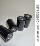 Small photo of four black capacitors. two standing and two lying with a white background. there is a terminal pin above the capacitor. it is an electronic component