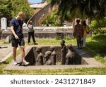Small photo of Stone Town Zanzibar - Feb 4 2024: A western tourist visits the memorial sculpture to slaves at the old Slave Market, Stone Town, Zanzibar, Tanzania