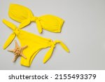 Beautiful yellow bikini on color background, top view.