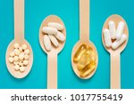 Healthy supplements on wooden teaspoons against pastel blue background