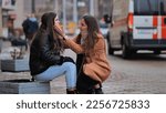 Small photo of The girl is crying on the street of the city. A sympathetic passer-by calms a lonely girl.