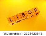 Small photo of LIBOR word text photo from wooden cube block letters isolated on yellow background. LIBOR is the acronym for London Interbank Offer Rate.