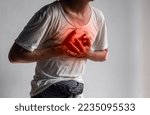 Small photo of Asian young man suffering from central chest pain. Chest pain can be caused by heart attack, myocardial infarct or ischemia, myocarditis, pneumonia, stress, etc.