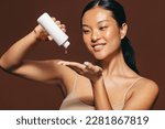 Small photo of Woman dropping face serum on her hand in the midst of her skincare routine. Young woman smiling as she applies a beauty treatment, which moisturizes and nourishes the skin for a radiant, flawless look