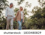 Romantic and elderly healthy lifestyle concept.Senior active caucasian couple holding hands looks happy in the park in the afternoon autumn sunlight,happy anniversary,happily retired with copy space.