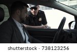 Small photo of Policeman stopping a driver in a car to question him through the window on a traffic offence