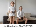 Funny caucasian siblings passionately playing video games in front of tv, two brother sister expressing emotions while enjoying their hobby playstation joystick. Copy space
