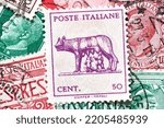 Small photo of Madrid, Spain; 09-22-2022: Postage stamp from Italy, with the image of the legend of Romulus and Remus suckled by a she-wolf, forming a background together with other stamps