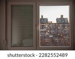 Small photo of Selective blur on PVC windows, in plastic, one covered with roller shutters, in an urban environment of Serbia with residential high rise buildings in background.
