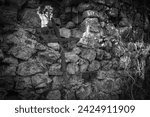Small photo of Twisted iron cross in the knave of a ruined chapel. In black and white.