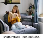 Woman sitting on couch and reading book. Social media detox. Slow living lifestyle. Mental wellbeing on quarantine. Happy female enjoying literature. Calm bookworm spending day off gadgets