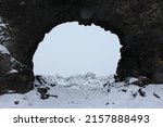 Rock lava arch in the lava field of Dimmuborgir area surrounded by snow and ice during a cloudy winter day near Mývatn Lake, northern Iceland, Europe