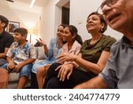 Small photo of An Indian mother explains the game to her daughter, as they watch a cricket natch with the entire family in their home in Mumbai, India.