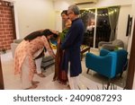 An Indian wife and her husband, dressed in traditional Indian wear, touch the feet of their parents while seeking blessings at the end of dinner at their home in Mumbai, India.