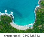 Small photo of aerial top view amazing freedom beach small white sand beach with perfect nature. white wave hit the rock around island. green forest peaceful. green sea, and clear sand landscape. Paradise beach.