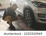 Mechanic checking geometry and suspension of a car wheel using precision tools. High-quality photo