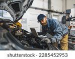Auto mechanic uses laptop while conducting diagnostics test. Modern car service. Computer diagnostics of the car. High quality photo