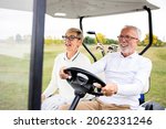 Portrait of healthy retired senior couple driving golf car to the green zone and enjoying free time outdoors.