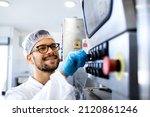 Small photo of Food factory worker in sterile uniform and hairnet operating industrial production machine.