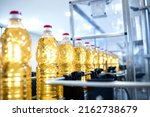 Bottled vegetable oil on conveyor automated machine being produced in food production plant.