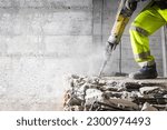 Small photo of Construction worker using heavy-duty jackhammer tool and breaking reinforced concrete. Demolishing building interior. Under construction.