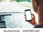 Hipster man looking on navigation map in car, tourist traveler driving, holding in male hands smartphone gps with clean screen display, panoramic view way road, trip in transportation from window auto