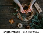 Christmas composition. Woman making handmade christmas wreath on dark wooden rustic table. The concept of preparation for the happy holidays. Festive interior decor. Top view, flat lay with copy spase