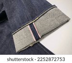 Small photo of Close up of red selvedge denim jeans with rolled up. Classic raw japan redline selvage denim jeans.