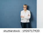 Small photo of Serious woman standing with folded arms over a blue background looking intently at the camera with a stern implacable expression with copyspace