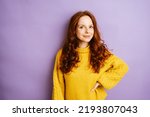 Young redhead woman looks at camera smiling, copy space