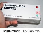 Small photo of Purwokerto, Indonesia - March 10, 2020: Hand holding Ambroxol Hcl drug box. Ambroxol is a drug that breaks up phlegm, used in the treatment of respiratory diseases associated with viscid or excessive.