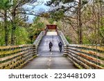 Small photo of A pair of cyclists, seen from behind and at a distance, ascend a bridge on the Silver Comet Trail near Atlanta, GA.
