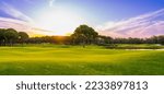 Small photo of Panorama of golf course at sunset with beautiful sky. Scenic panoramic view of golf fairway. Golf field with pines