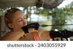 Small photo of Sport woman in shooting range with bow. Outdoor archery training. Practice and training of archery in shooting range. Athlete keep wooden bow. Sportsman in shooting gallery aim an arrow to hit target