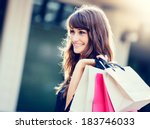 Happy woman holding shopping bags and smiling at the mall