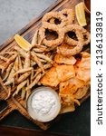 Seafood beer appetizers. Fried sprat, chips, shrimp, squid rings, lemon wedge, tomato sauce and tartar sauce