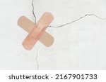 Small photo of A crosswise of two bandage is stuck to a crack in the concrete wall. The concept of recovery or treatment