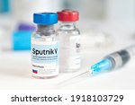 Small photo of The vaccine Sputnik V from the coronovirus infection covid 19 on a blue background and a syringe on the table. January 18, 2021, Barnaul, Russia.