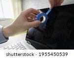 Small photo of Human hand blocks a webcam of laptop by an adhesive tape. persecution mania, persecution complex, delusion of persecution. Spying on privacy via webcam.