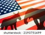 Small photo of Democrats vs republicans are in a ideological duel on the american flag. In American politics US parties are represented by either the democrat donkey or republican elephant. animal shadows on flag