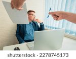 Small photo of A sad businessman in a suit sits in the office and looks at the documents. Conclusion of a contract with the boss. Unwillingness to sign a contract. Dismissal of an employee.